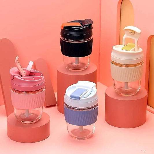 Four colorful glass cups with lids on pink stands against a pink background